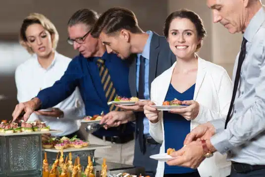 business people taking snacks from buffet table